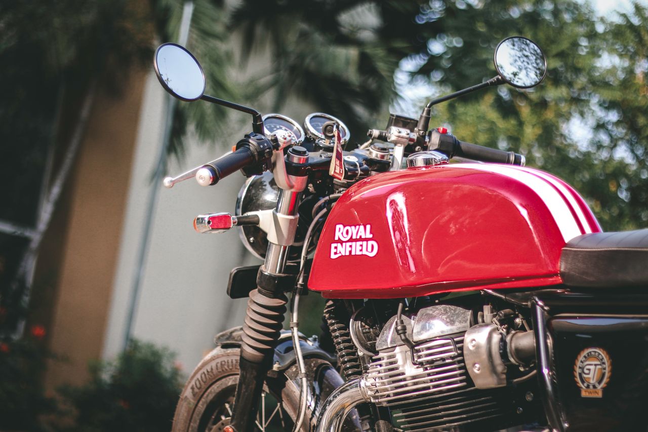Close-up of a red Royal Enfield motorcycle outdoors, showcasing its details.