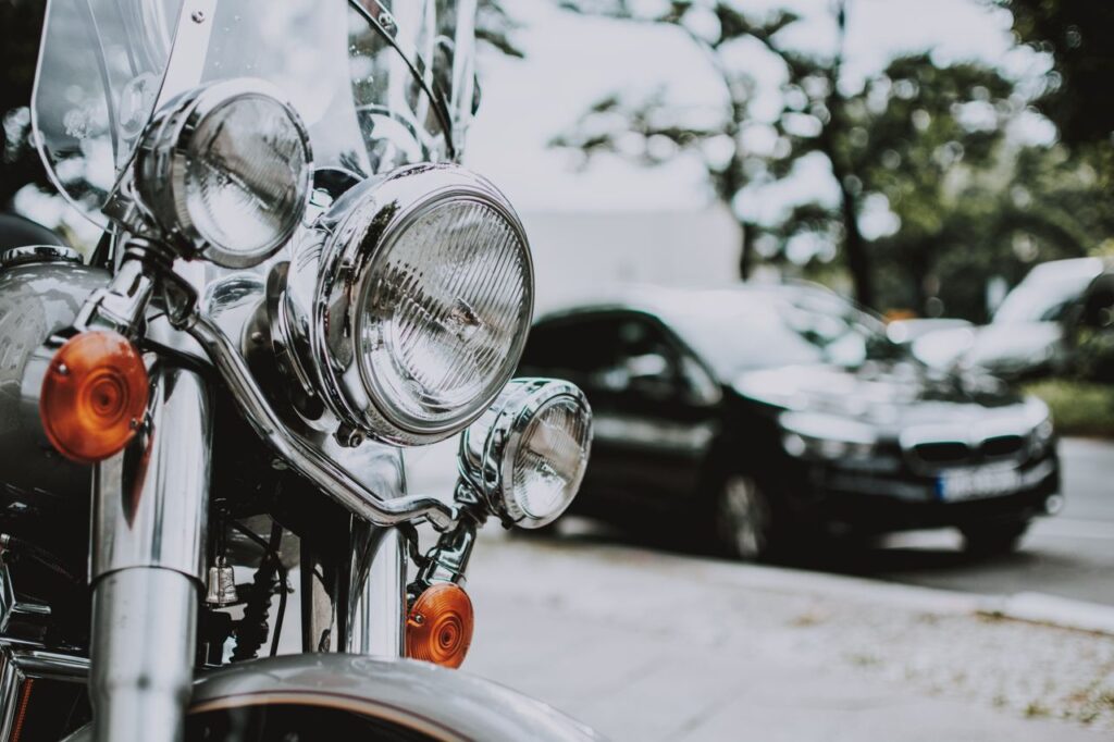 Headlights of motorbike with black car on asphalt road on background in city street
