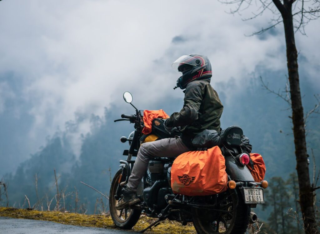 Rider on a motorcycle enjoying a misty mountain view, showcasing adventure and exploration.
