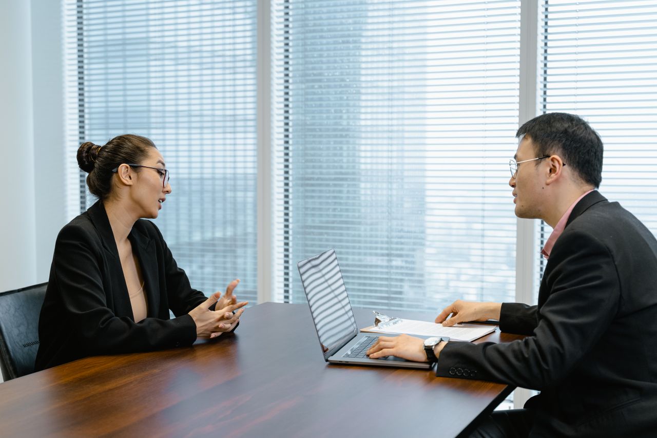 Two colleagues in a professional meeting discussing business strategy at an office table.